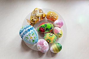 Colorful Easter eggs with floral ornaments, origami decorations and crewel wool against white background