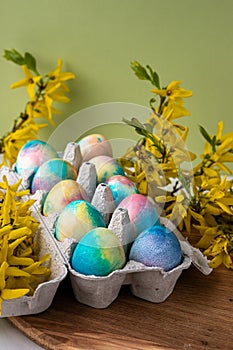 colorful Easter eggs on a green background next to yellow flowers