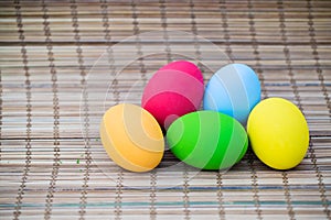 Colorful easter eggs on nature bamboo mat background. symbol of easter`s day festival. vivid color natural background. festive wal