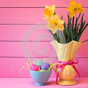 Colorful Easter Eggs in Nest with Daffodils in Vase on Pink Boards Background with room or space for copy, text, or your words.