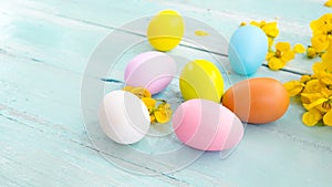 Colorful Easter eggs in nest with flower on rustic wooden planks background