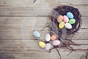 Colorful Easter eggs in nest on rustic wooden planks background.