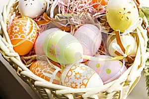 Colorful Easter eggs with ornate in decorative nest basket.