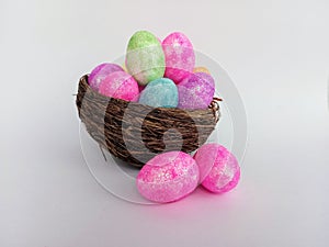 Colorful Easter eggs overflowing a twig birds nest on a white background