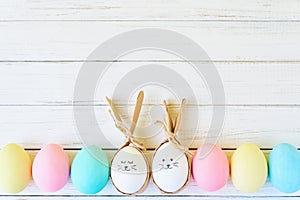 Colorful easter eggs with painted faces and bunny ears in row on a white background