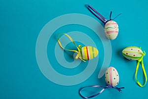 Colorful Easter eggs with ribbon on a blue background. Copy space next to the eggs, top view