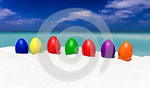 Colorful easter eggs in a row on a tropical beach