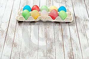 Colorful easter eggs in a tray over wooden background. Space for text. Easter card.