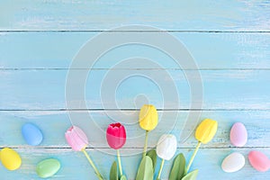 Colorful Easter eggs with tulip flower on blue wooden background.