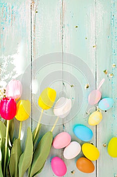 Colorful Easter eggs with tulip flower on rustic wooden planks background.
