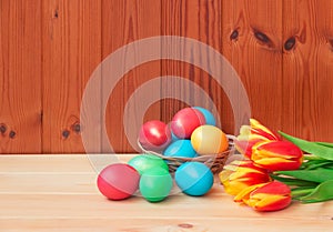 Colorful Easter eggs and tulip flowers on wooden background. Selective focus