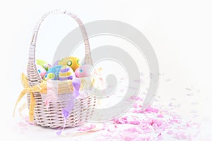 Colorful Easter eggs in white basket and pink delicate blossoms