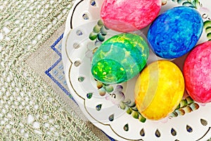 Colorful Easter eggs in white ceramic bowl on the table