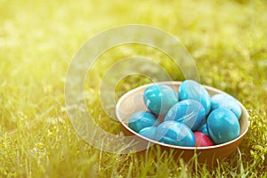 Colorful Easter eggs in a wooden basket in grass