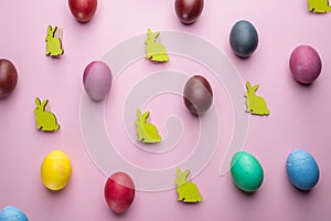 Colorful Easter eggs and wooden Easter Bunnies as attribute of Easter celebration. Pink background