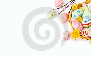 Colorful Easter eggs with yellow flowers and willow twigs on white background.