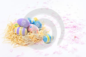 Colorful Easter eggs in yellow nest and pink blossoms