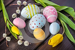 Colorful Easter eggs with yellow Tulip hand painted on a dark wooden background. Holiday spring card
