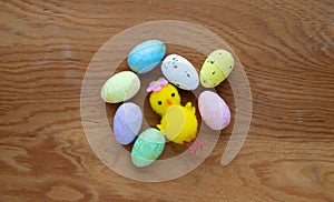 Colorful Easter toy eggs and a yellow toy chicken on a wooden background.The Concept Of Easter