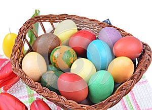 colorful eggs in a basket and colorful tulip decorations on an isolated white