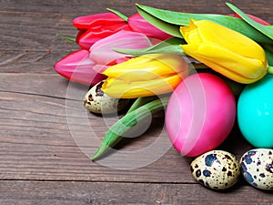 Colorful eggs with tulips on a wooden background