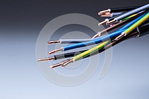 Colorful electrical cables with copper wiring ending on isolated grey background