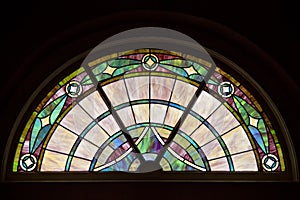 Colorful, elegant patterned stained glass window in circle top design.