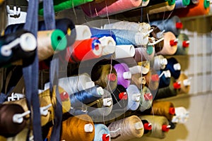 Colorful embroidery thread spool using in garment industry, row of multicolored yarn rolls, sewing material selling in