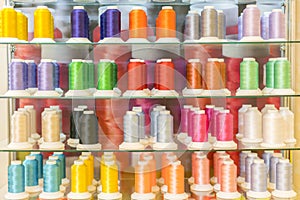 Colorful embroidery thread spool using in garment industry, row of multicolored yarn rolls, sewing material selling in the market.