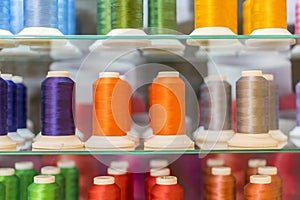 Colorful embroidery thread spool using in garment industry, row of multicolored yarn rolls, sewing material selling in the market.