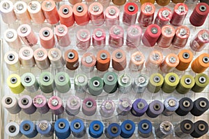 Colorful embroidery thread spool using in garment industry, row of multicolored yarn rolls, sewing material selling in the market