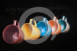 Colorful empty ceramic cups hanging on wall