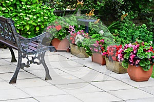 Colorful English patio area with planters and iron bench. photo