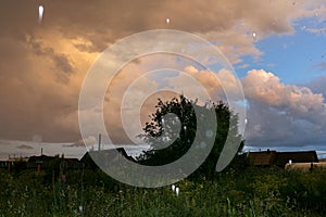 Colorful evening sky and small hail after thunderstorm over village.