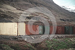 Colorful export import cargo shipping container standing next to each other next to the road at Seydisfjordur, Iceland, wide angle