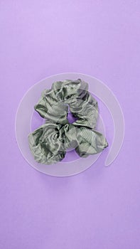 Colorful fabric hair band isolated on purple background. Olive green hair band. Satin green fabric hair band. photo