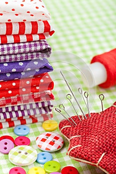 Colorful fabrics, buttons, pin cushion, thimble, spool of thread - set for sewing