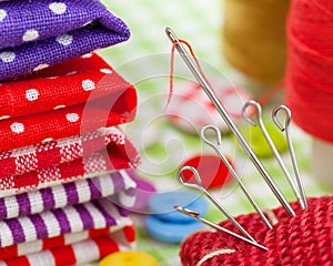 Colorful fabrics, buttons, pin cushion, thimble, spools of thread for sewing