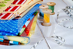 Colorful fabrics with pins, measuring tape and rolling cotton threads
