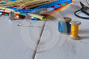 Colorful fabrics with vintage scissors, pins, measuring tape and rolling cotton threads