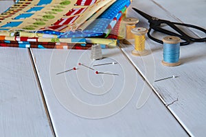 Colorful fabrics with vintage scissors, pins, measuring tape and rolling cotton threads
