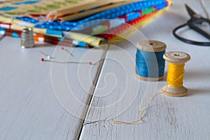 Colorful fabrics with vintage scissors, pins, measuring tape and rolling cotton threads