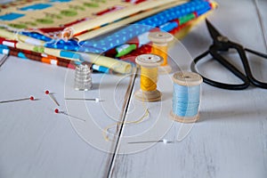 Colorful fabrics with vintage scissors, pins, measuring tape and rolling cotton threads