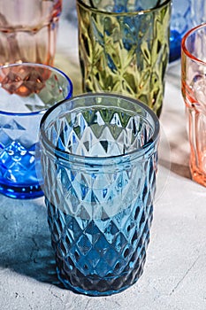 Colorful faceted and geometric drink glass, group of empty green, red, blue and transparent drinkware for beverage