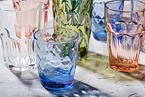 Colorful faceted and geometric drink glass, group of empty green, red, blue and transparent drinkware for beverage