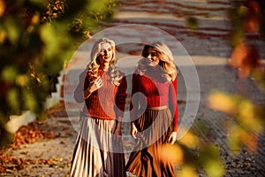 Colorful fall. female beauty. real femininity. autumn women outdoor. girl friends walk in park. sunny day with fallen