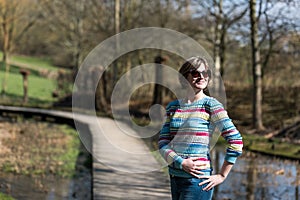Colorful fashion shoot of a 30 year old woman with a colorful jersey and sunglasses in a nature background