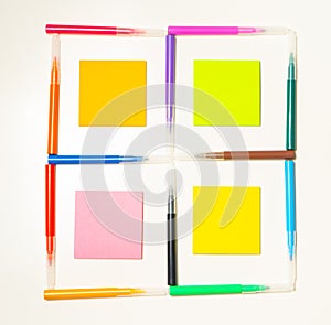 Colorful felt-tip pens on the white background. Markers and stickers pattern in the shape of square.