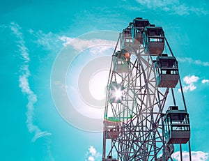 Colorful ferris wheel of the amusement park in the blue sky background