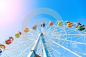 Colorful ferris wheel of the amusement park in the blue sky background